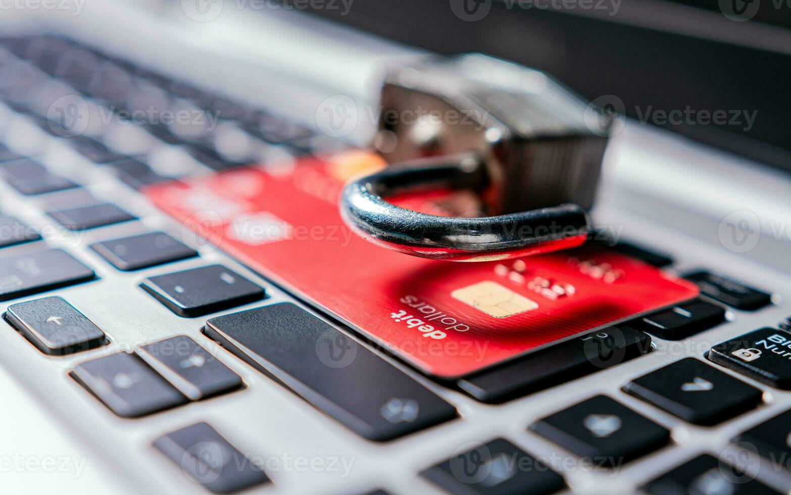 Padlock on top of credit card on laptop keyboard. Open padlock with credit card on keyboard. Concept of theft of information on credit cards photo