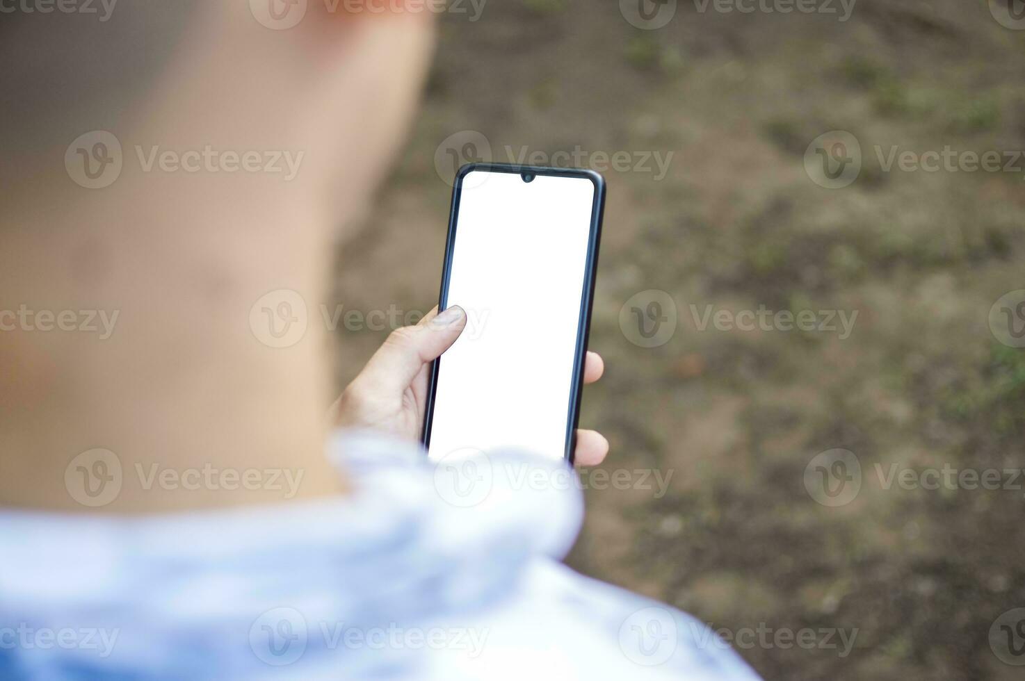 cerca arriba de un hombre con célula teléfono en mano, cerca arriba Disparo de un persona comprobación su célula teléfono, joven chico con célula teléfono en mano con Copiar espacio foto