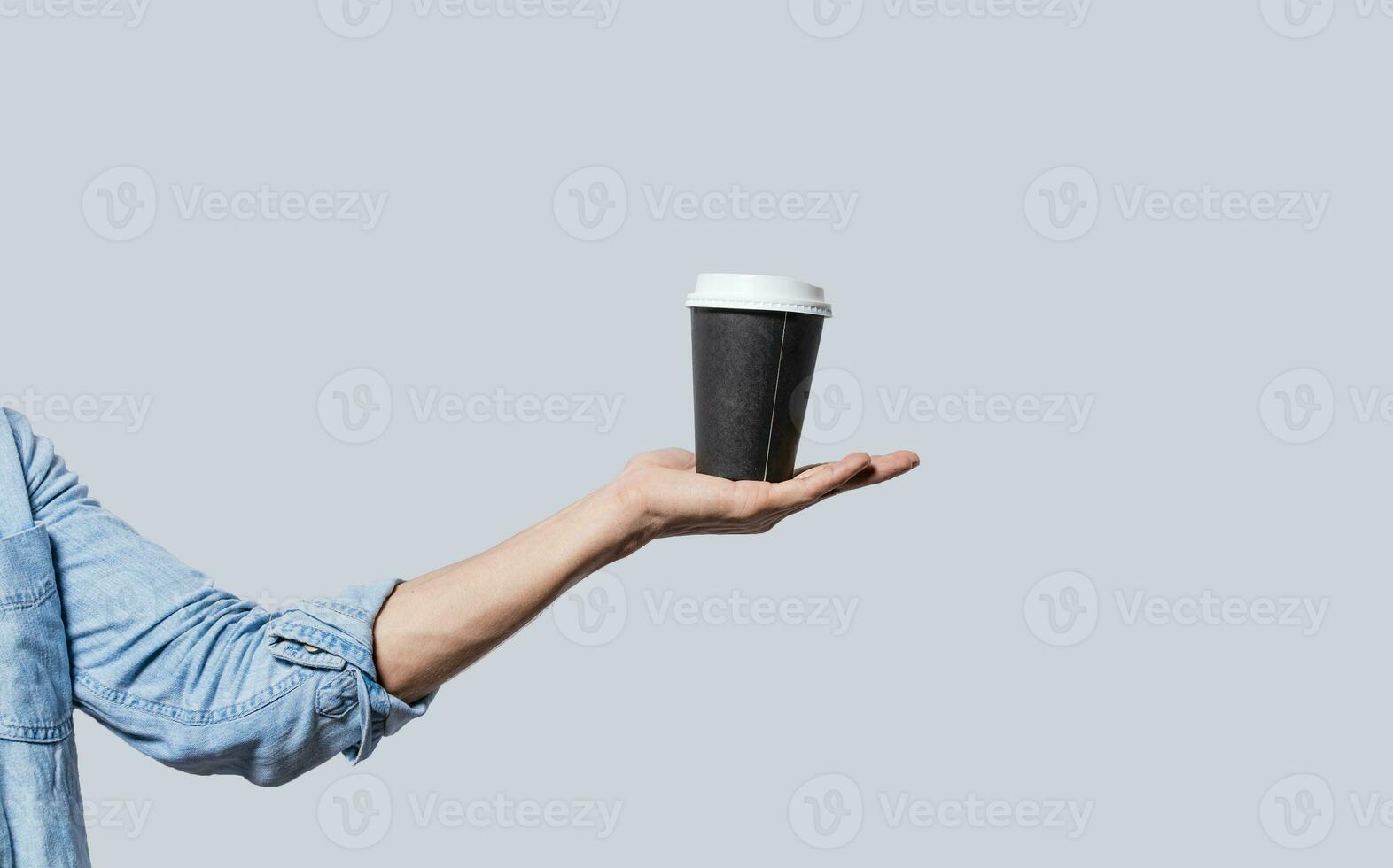 Hand holding a coffee to go on isolated background, Close up of hand holding a paper cup of coffee.  Arm holding glass of coffee isolated photo