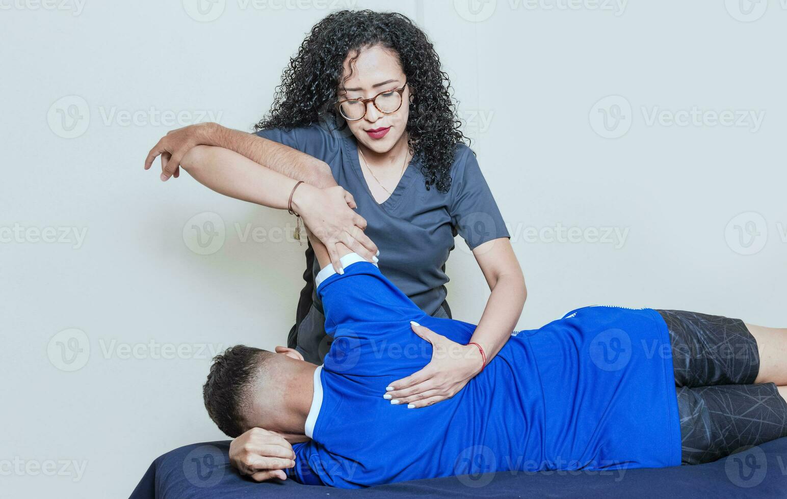 Back rehabilitation physiotherapy, smiling female physiotherapist practicing back rehabilitation to patient, Physiotherapist with patient on back treatment photo