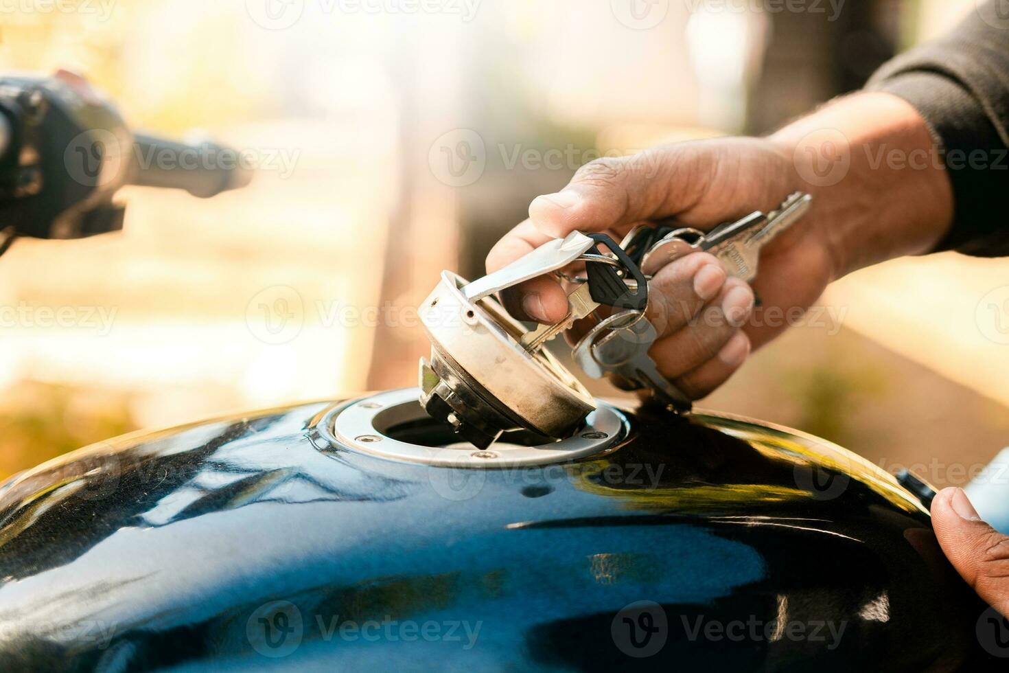 Hands opening the gas tank of the motorcycle with the key. Hand opening the gas tank of the motorcycle, Motorcyclist opening the gas tank of the motorcycle. photo