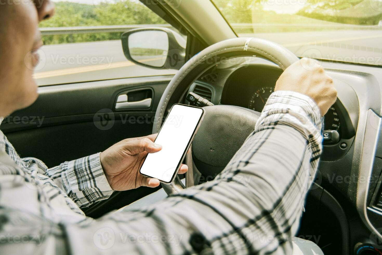 Man using his phone while driving, Person holding the cell phone and with the other hand the steering wheel, Concept of irresponsible driving, Distracted driver using the cell phone while driving photo