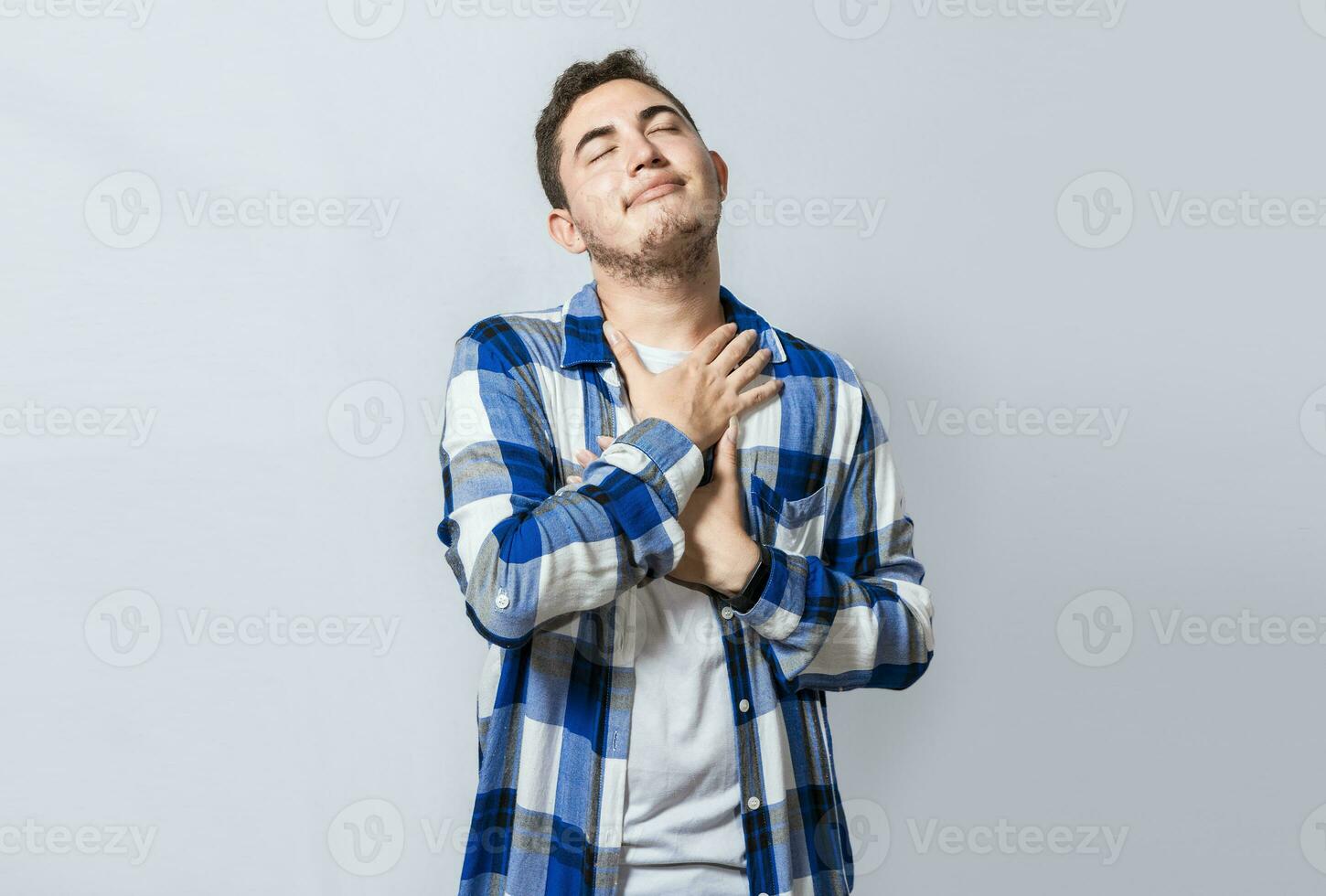 Grateful young guy smiling with hands on chest, isolated. Positive young man with charming sincere smile feeling grateful. relaxed person with gesture of thanks with hands on chest photo