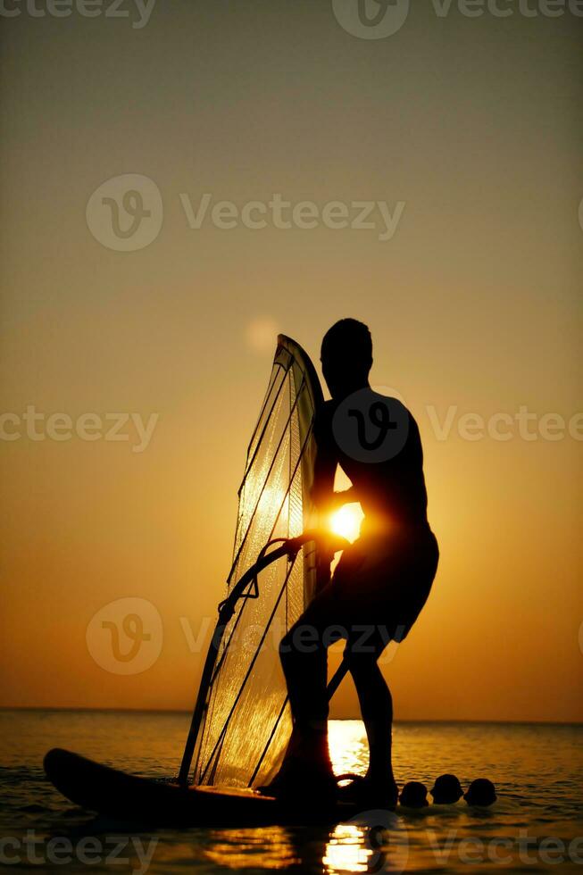 Man sailboarding at sunset photo