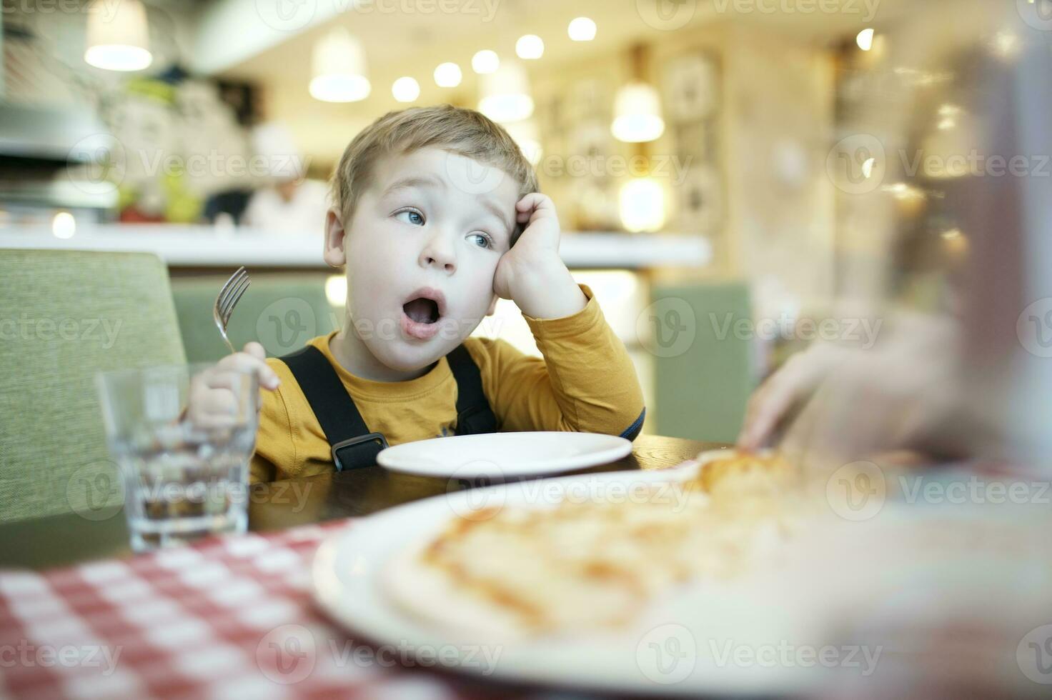 Young boy yawning as he waits to be fed photo