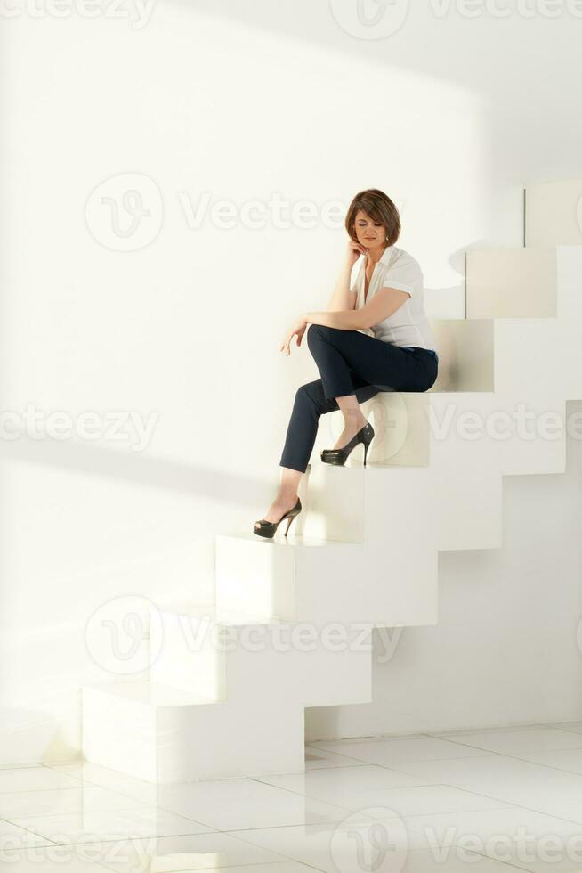 Adult businesswoman sitting on steps and looking down photo