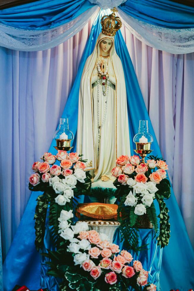 Statue of the Virgin Mary and the crown on the background of a blue curtain photo