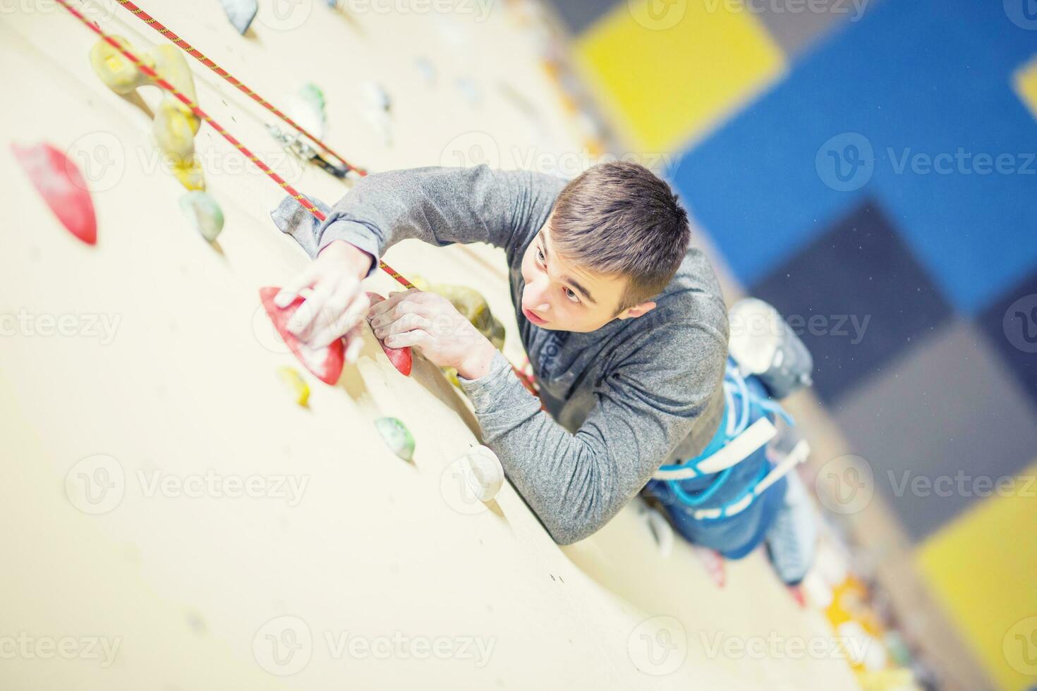 Climber on wall.Young man practicing rock climbing on a rock wall indoors photo