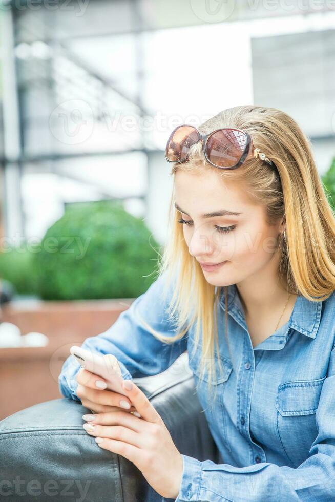 Girl texting on the smart phone in a shpping mall sitting in internet free zone photo