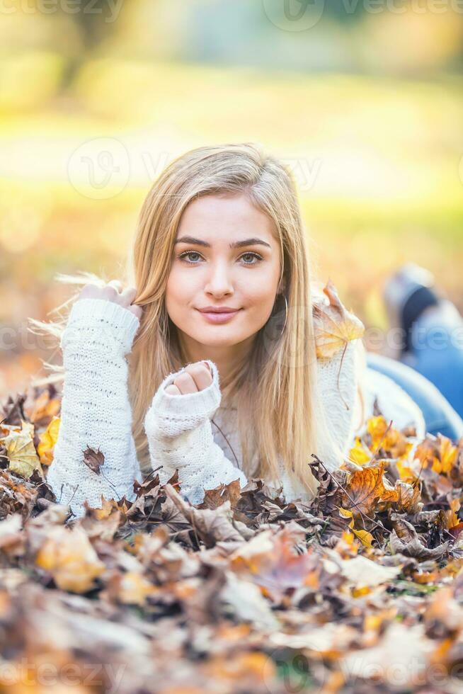 otoño retrato de joven mujer acostado en arce hojas en parque foto