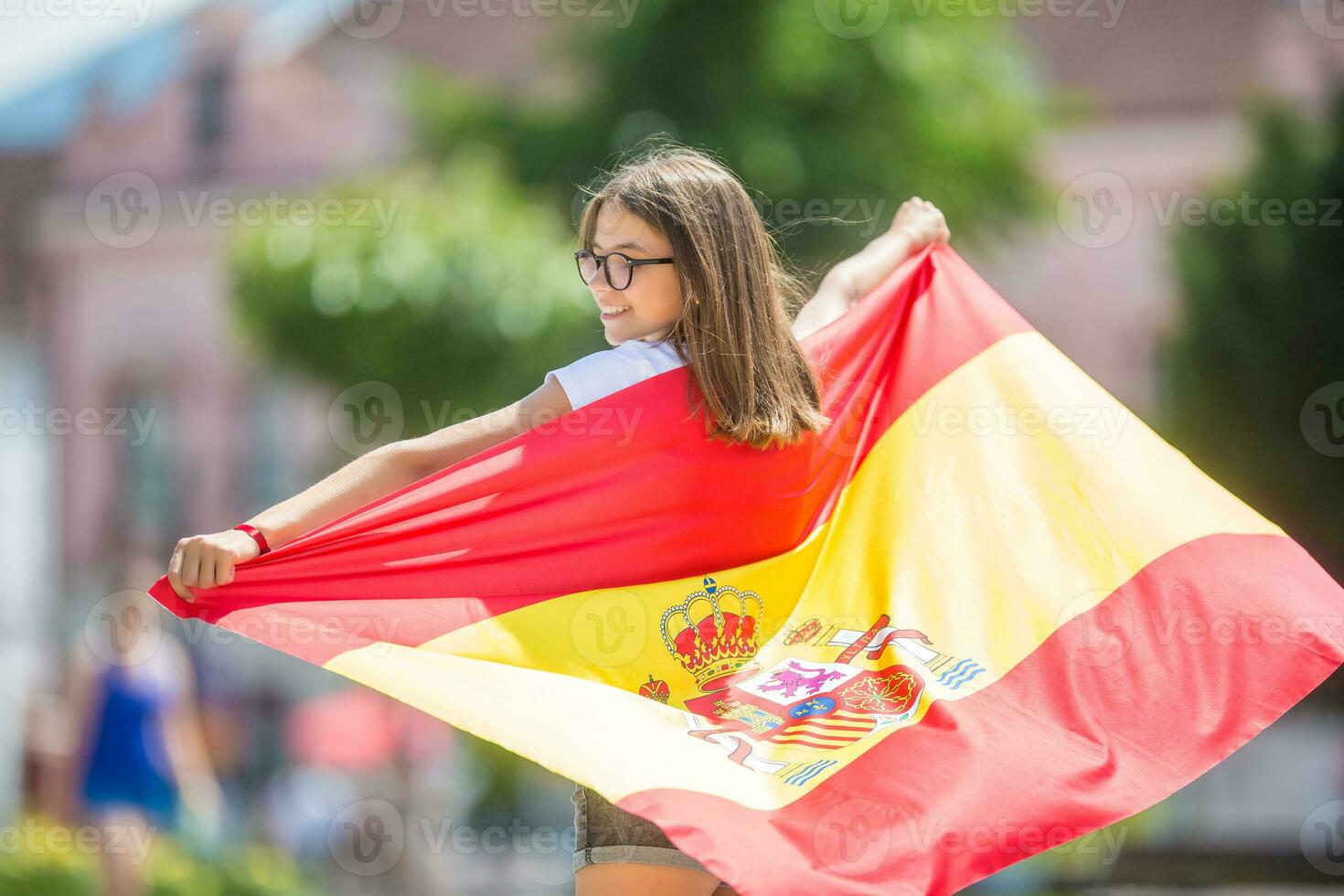 Happy girl tourist walking in the street with spanish flag photo