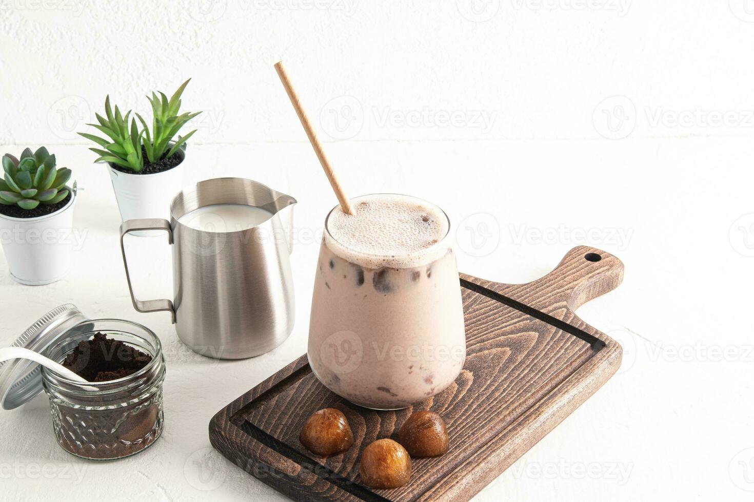 Delicious coffee latte, iced mocha in a large beautiful glass with eco straw stands on a wooden board. trendy pieces of coffee ice. still life. photo