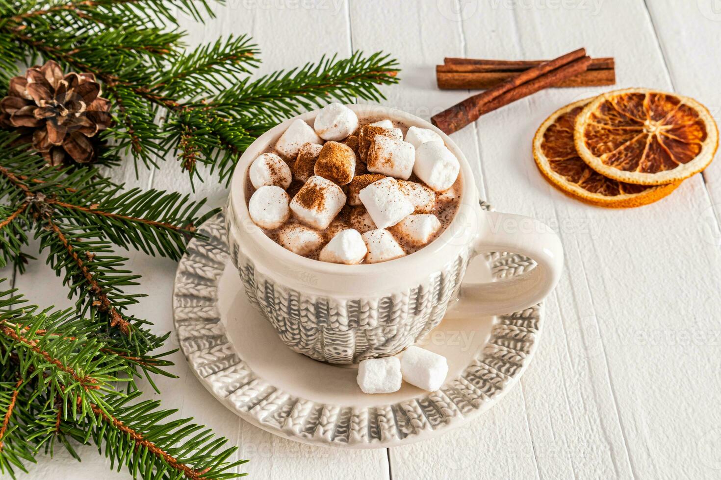 Beautiful cup with New Year knitted pattern with hot cocoa or chocolate drink with marshmallows on white wooden table. concept of cozy Christmas. photo