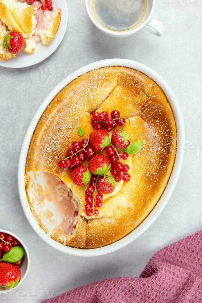 Homemade casserole with cottage cheese, semolina, fresh red currant and strawberry on light gray background. Top view. photo