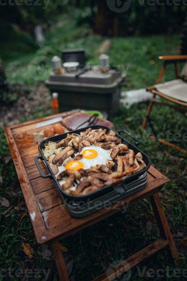 Fried eggs and grilled pork in a camping pan photo