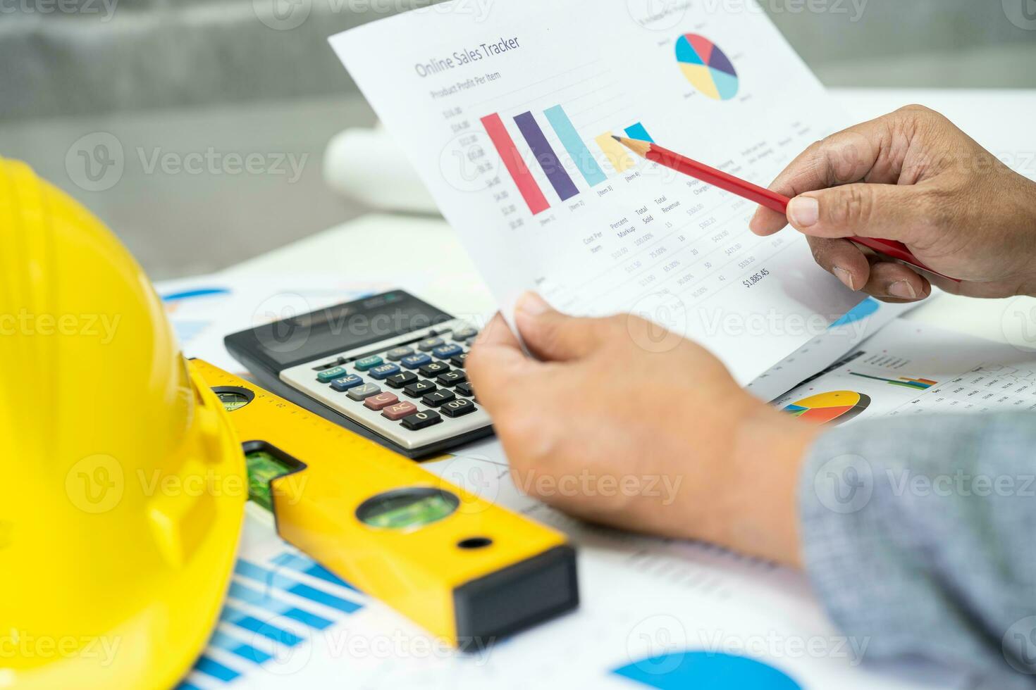 Asian engineer with architectural house plan project blueprint, graph and yellow helmet and engineering construction tools. photo