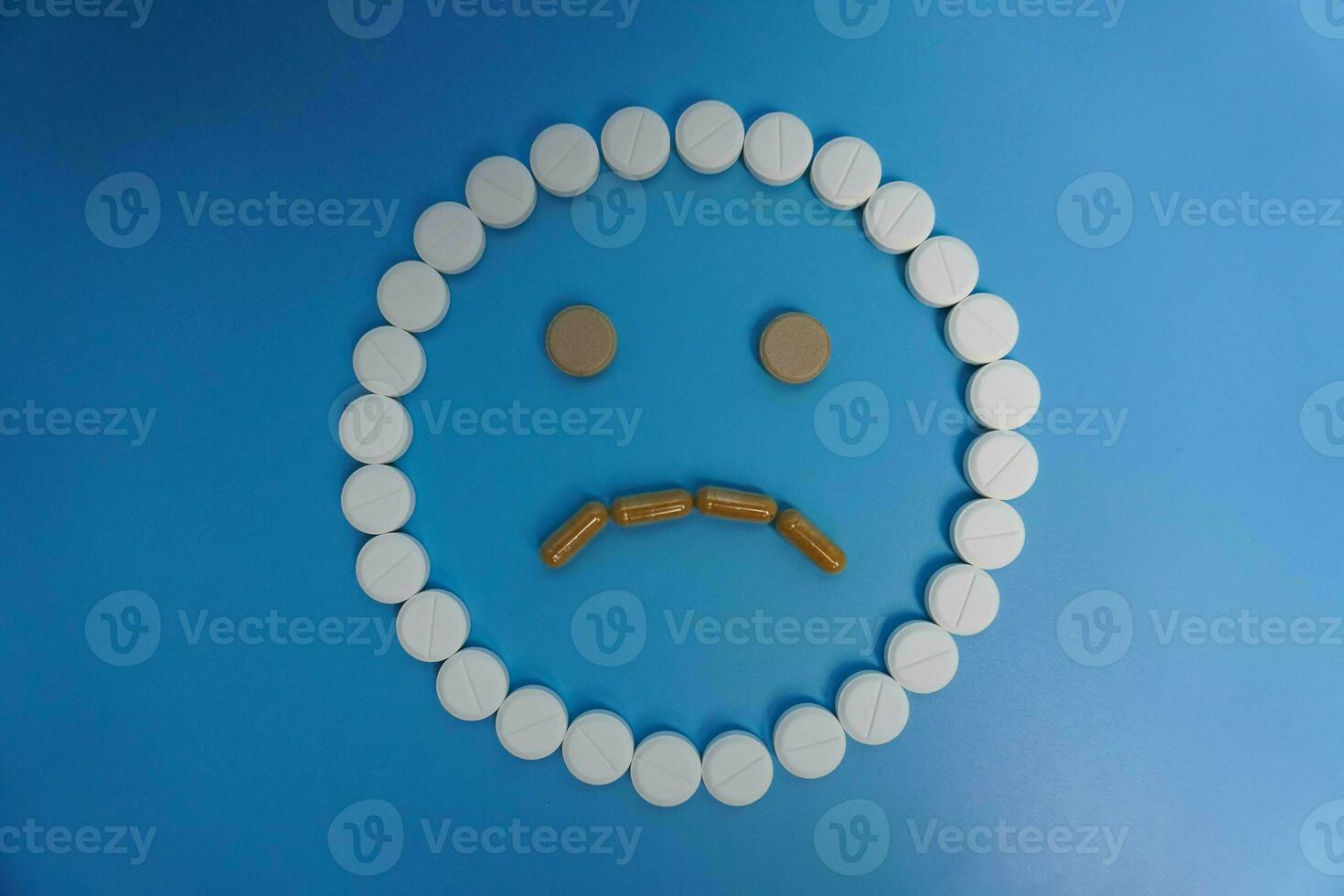 negative smile made of pills, tablet, capsule on blue background. Concept of medicine, pills, treatment, medical insurance. sad concept photo