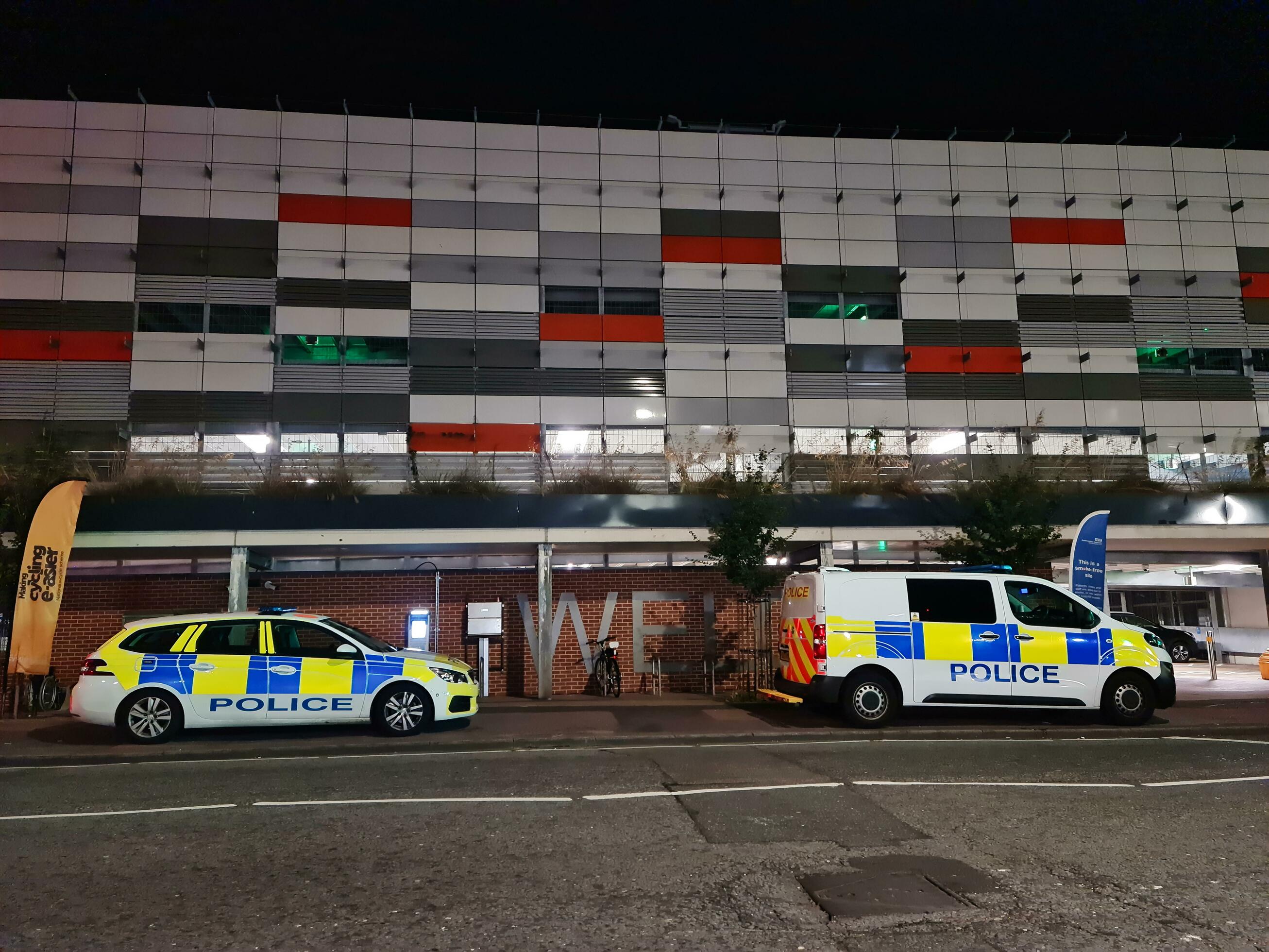Low Angle View of 2 Police Cars at Illuminated Road and Car Park