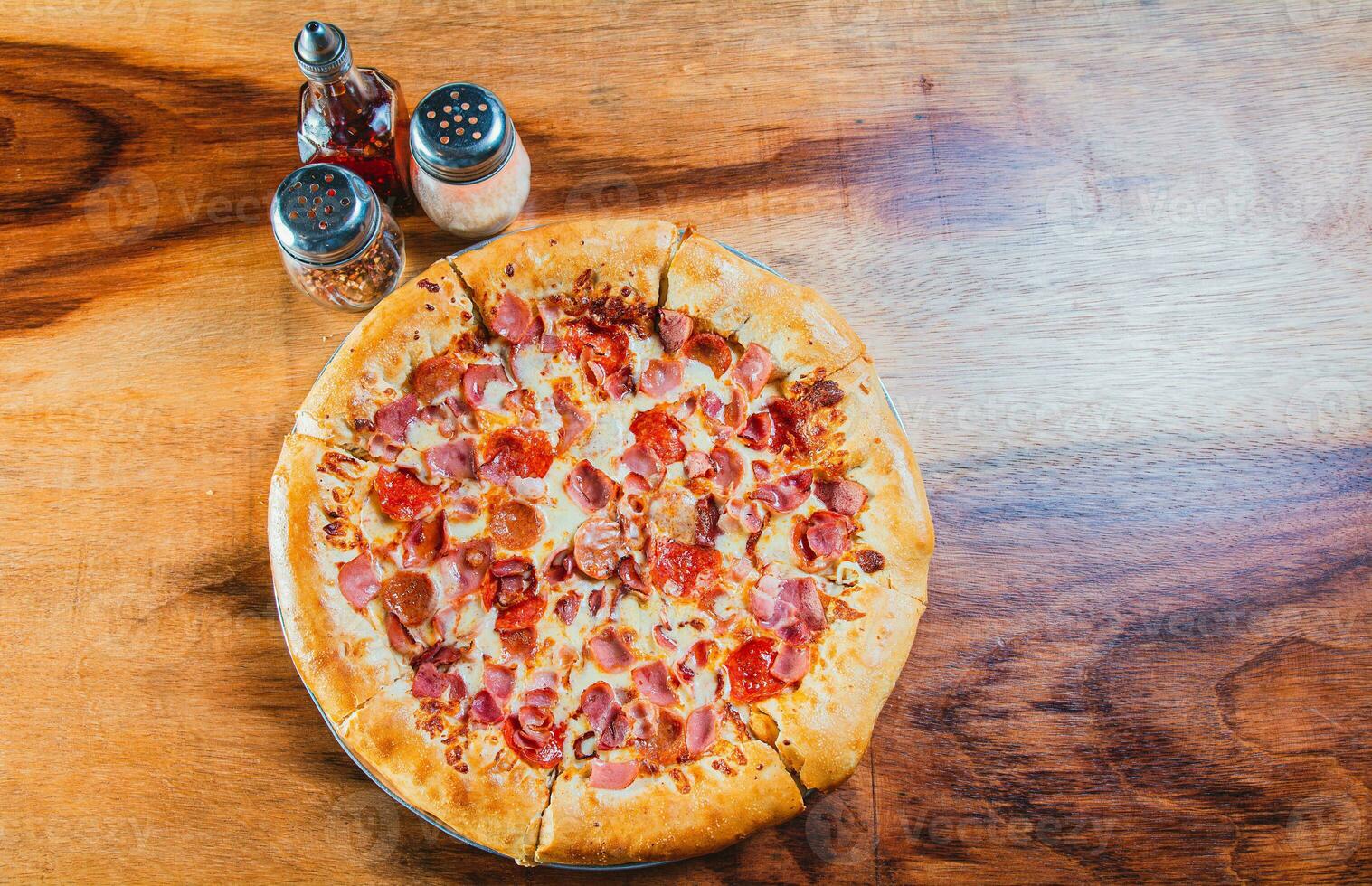 Top view of ham and cheese pizza on wooden table. Ham pizza with cheese edge on wooden background photo