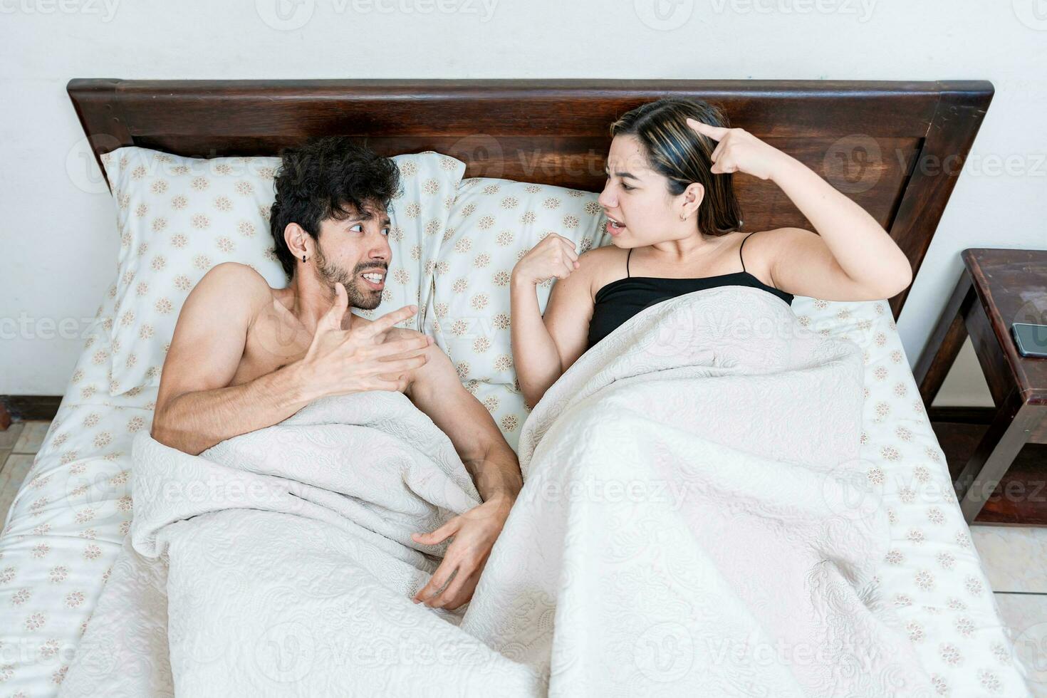 Upset couple lying in bed arguing. Top view of young couple lying in bed arguing. Upset couple lying in bed arguing. Marriage problems concept photo