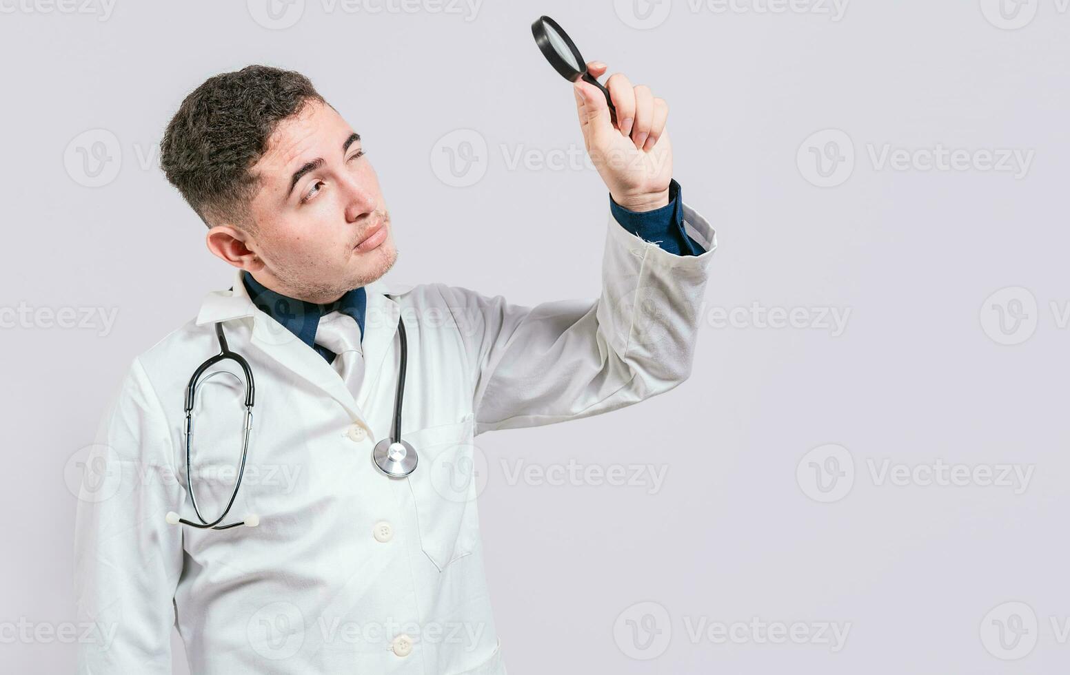 Doctor looking for something with magnifying glass looking isolated. Handsome Doctor holding magnifying glass and looking for something photo