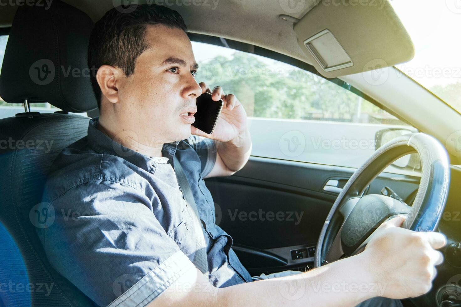 Concept of man calling on the phone while driving, A man driver calling on the phone in his car, Close up of a young man sitting inside car using mobile phone photo