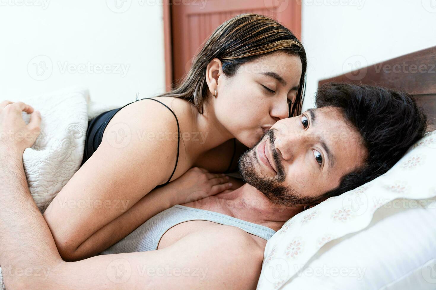 Woman in bed kissing her husband on the forehead. Wife in bed kissing husband on the forehead photo