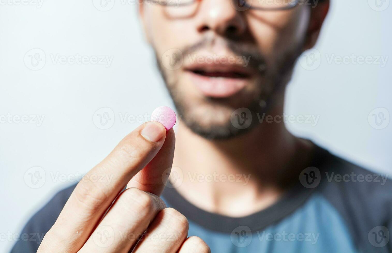 Close up of young man holding aspirine. Self-medication concept, Man putting a pill in his mouth isolated, Close-up of a man taking an aspirin, Person taking a pill isolated photo