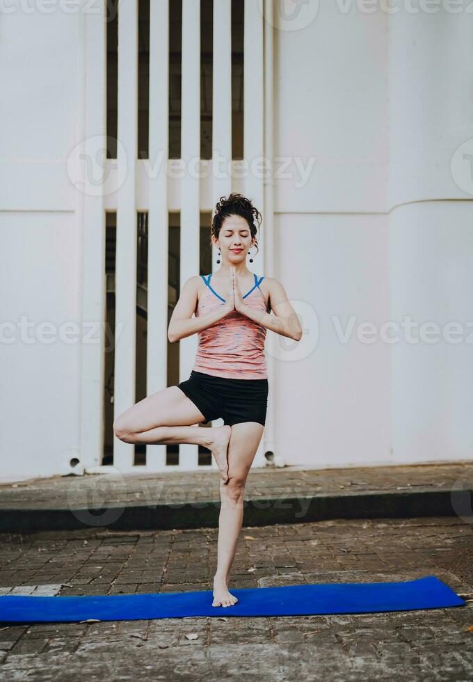 Young woman doing vrikshasana yoga outdoors. Girl doing yoga vrikshasana or tree pose outdoors. Relaxation and vitality yoga concept photo