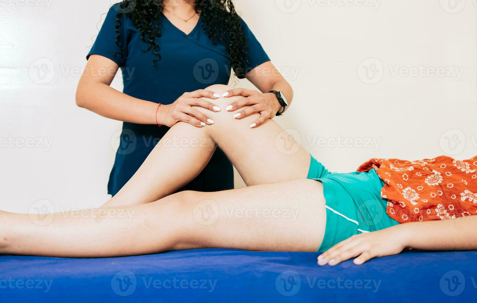 rodilla rehabilitación fisioterapia a paciente acostado abajo. hembra fisioterapeuta comprobación rodilla a hembra paciente. fisioterapeuta manos comprobación rodilla de hembra paciente foto