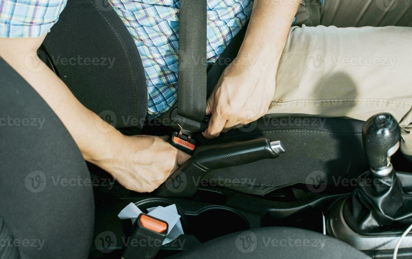 Close up of driver hands fastening the seat belt, Driver's hands putting on the seat belt. Safety belt for accident prevention. Close up of person's hands putting on the seat belt photo