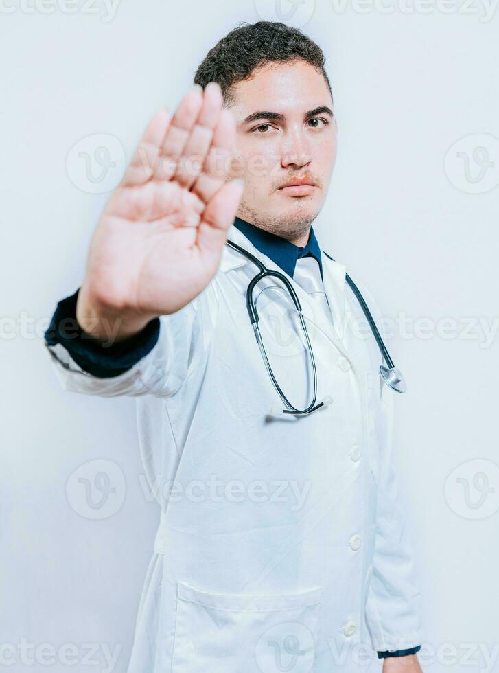 Handsome doctor making stop gesture isolated, Young doctor making stop gesture with palm of hand photo