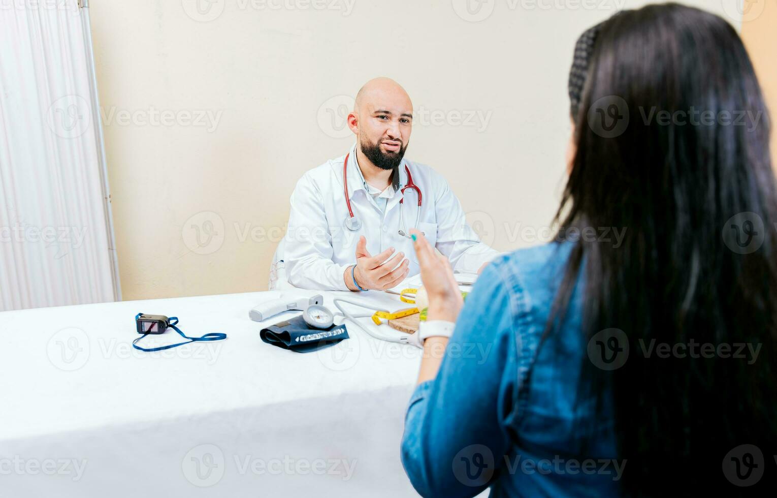 Back view of a female patient talking to the nutritionist. Smiling nutritionist explaining to a female patient, Nutritionist man talking to woman patient in office photo