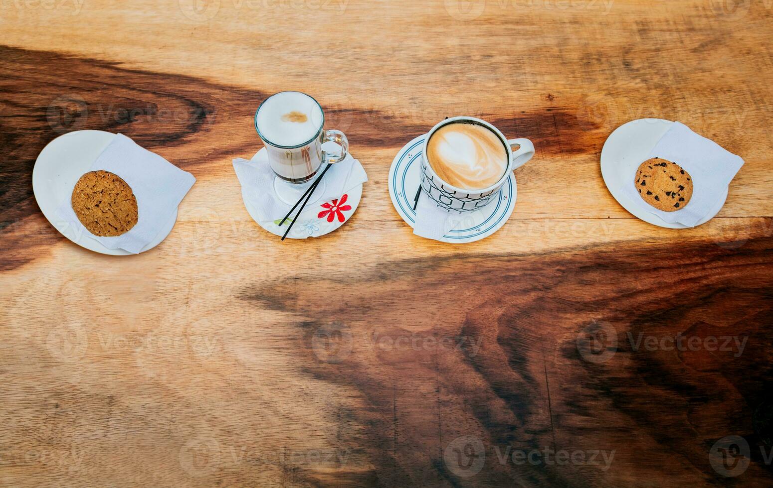 Top view of hot cappuccinos with cookie on wooden background. High angle view of cappuccinos with cookies on wooden table photo