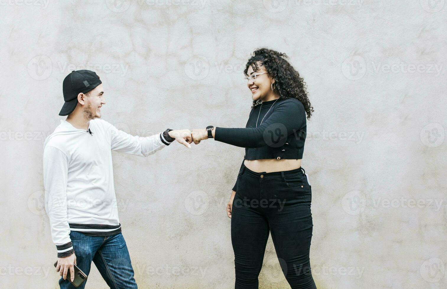 Two teenage friends bumping their fists. A guy and teenage girl shaking fists at each other, close up of two funny friends bumping fists in a friendly way photo