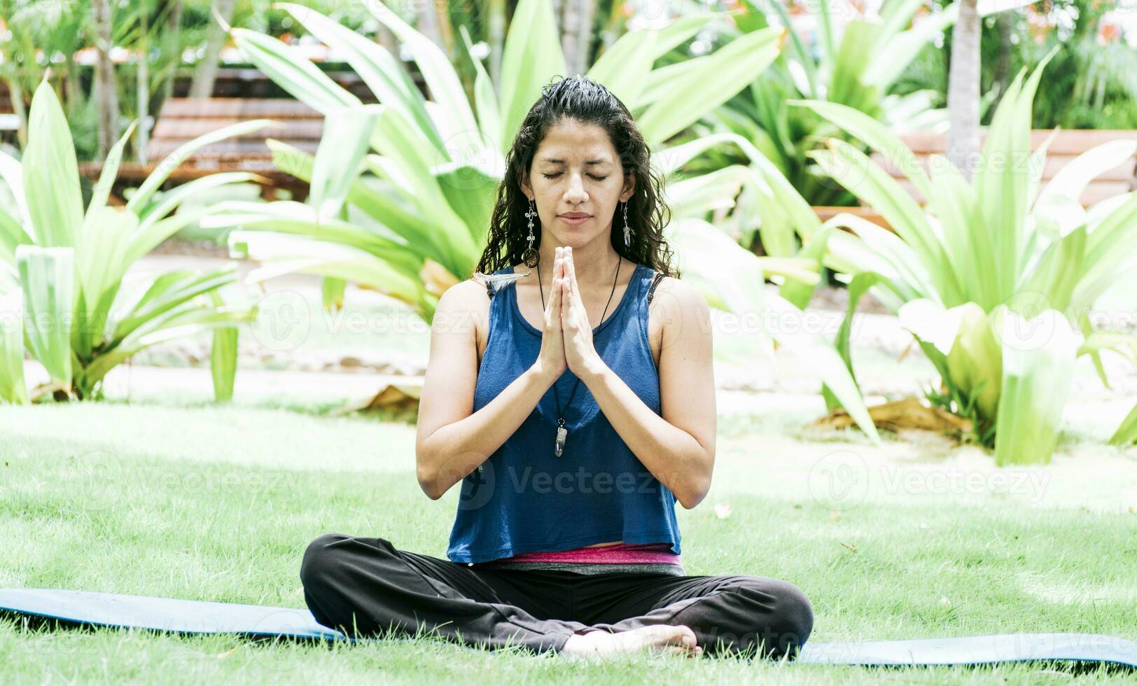 A girl sitting doing meditation yoga outdoors, Woman doing yoga outdoors, a young woman doing yoga with closed eyes. photo