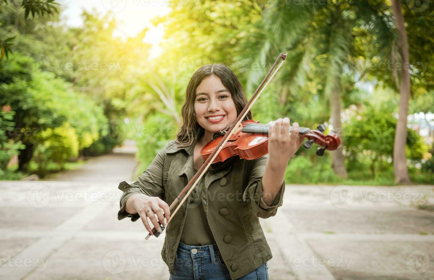 Young woman playing the violin outdoors. Portrait of a girl playing the violin outdoors, Close up of a girl with her violin playing a melody outdoors, Concept of smiling female violinist photo