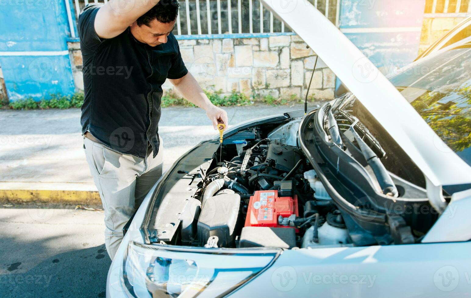 Man checking the oil in his vehicle. Person checking the oil level of his car in the street. Driver inspecting car oil level photo