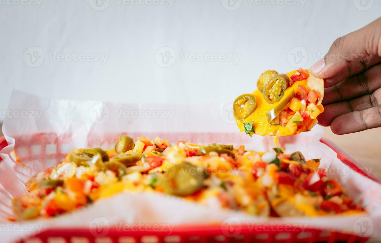 Hand taking nachos from a tray. Hand of people taking nachos on isolated background photo