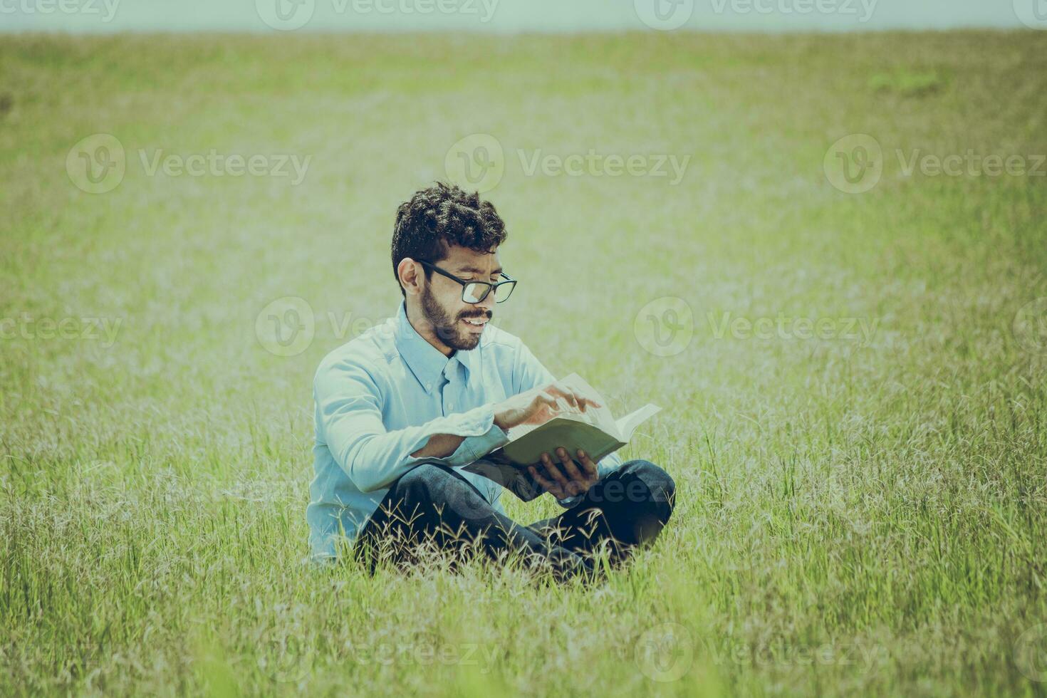 joven hombre en el césped leyendo un libro, un persona sentado en el césped leyendo un libro, concepto de personas leyendo fuera de foto