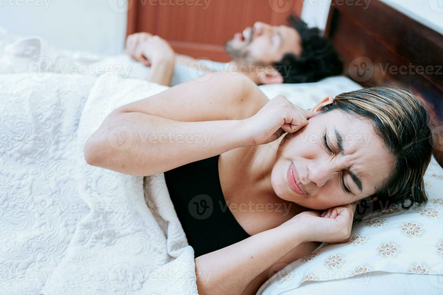esposa sufrimiento desde su dormido marido ronquidos. dormir apnea concepto, hombre ronquidos en dormitorio y esposa cubierta su orejas foto