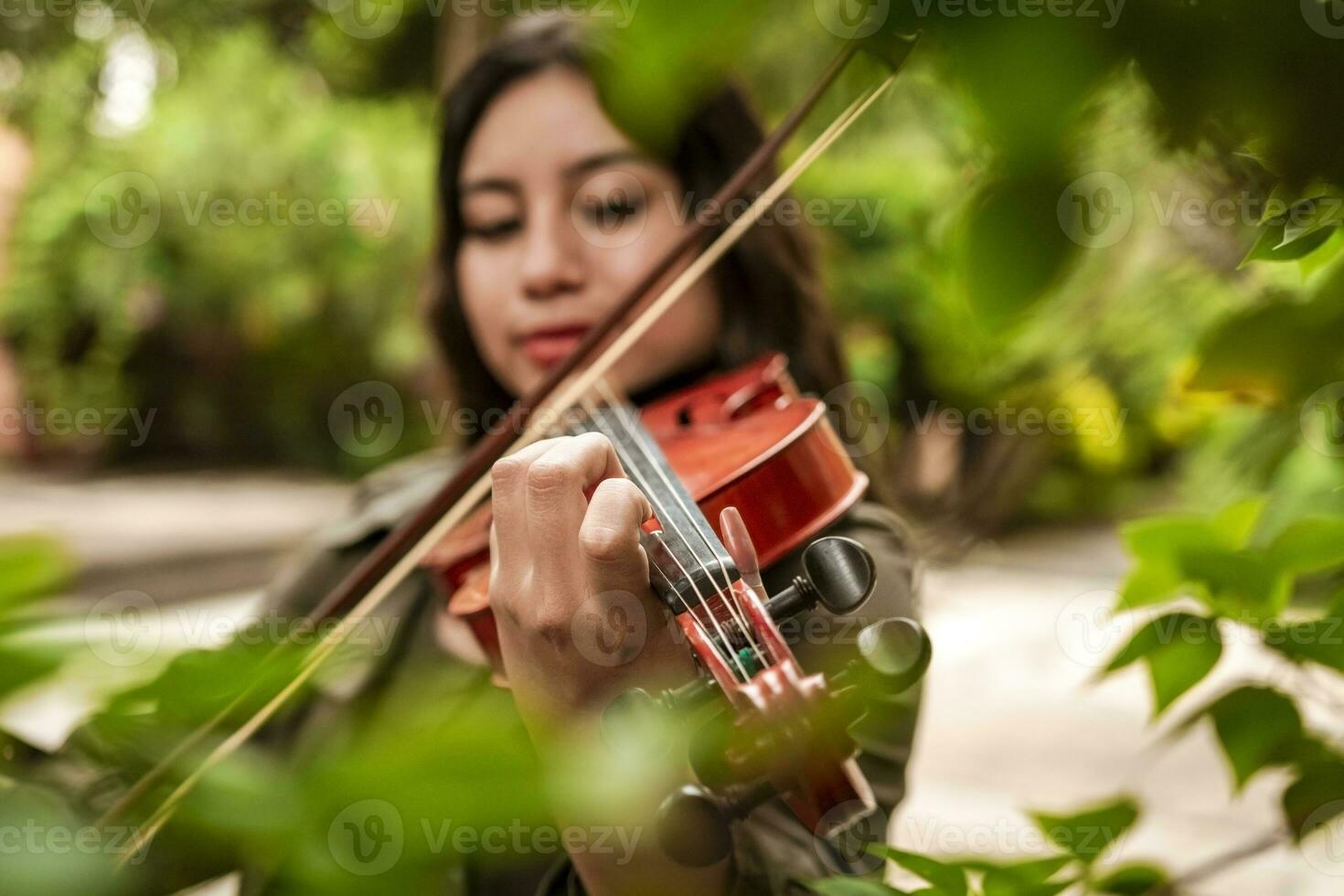 Girl with her violin playing a melody outdoors, Concept of smiling female violinist. Attractive girl playing the violin outdoors. Portrait of a girl playing the violin outdoors photo