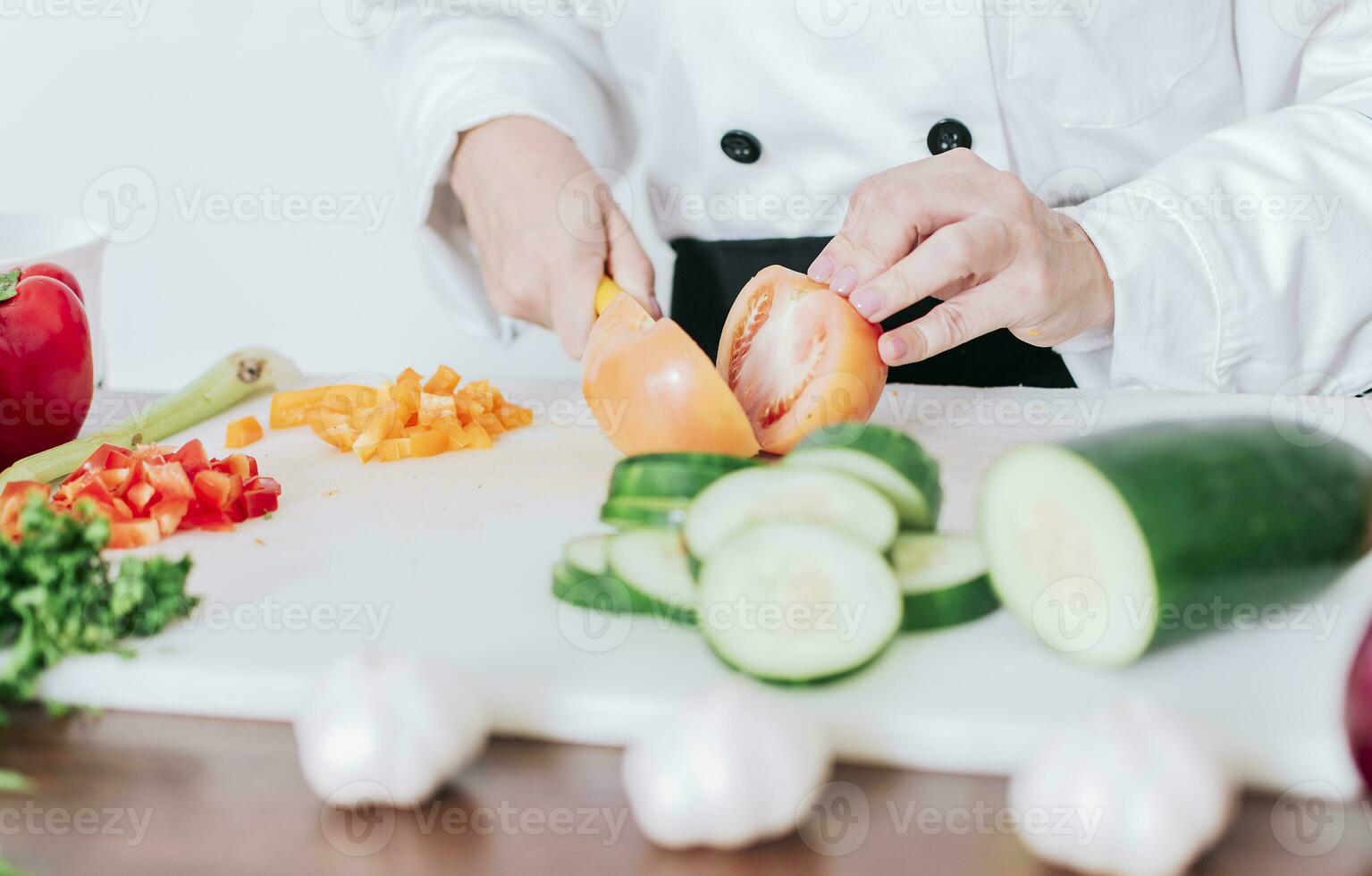 Close up of chef woman hands cutting tomatoes and vegetables, chef hands preparing and cutting vegetables. Chef woman hands cutting tomatoes and vegetables photo