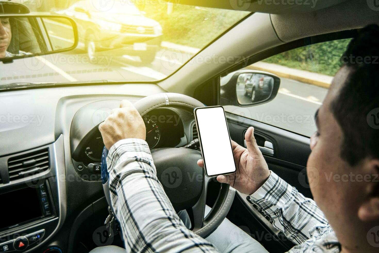 Distracted driver using the cell phone while driving, Man using his phone while driving, Person holding the cell phone and with the other hand the steering wheel, Concept of irresponsible driving photo