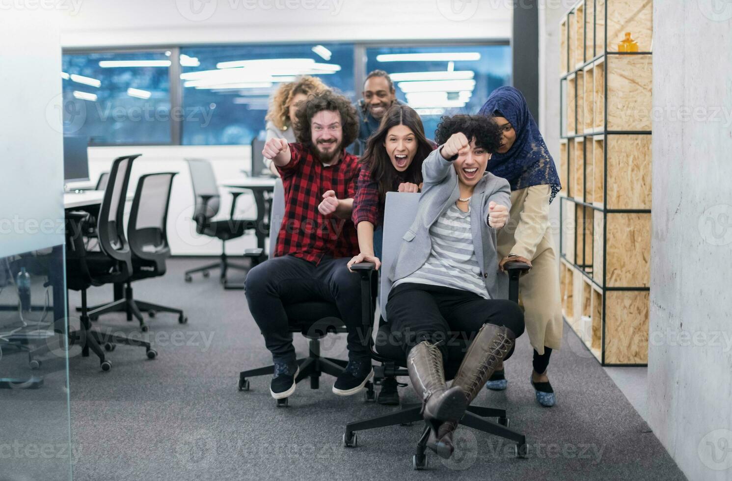 equipo de negocios multiétnico corriendo en sillas de oficina foto