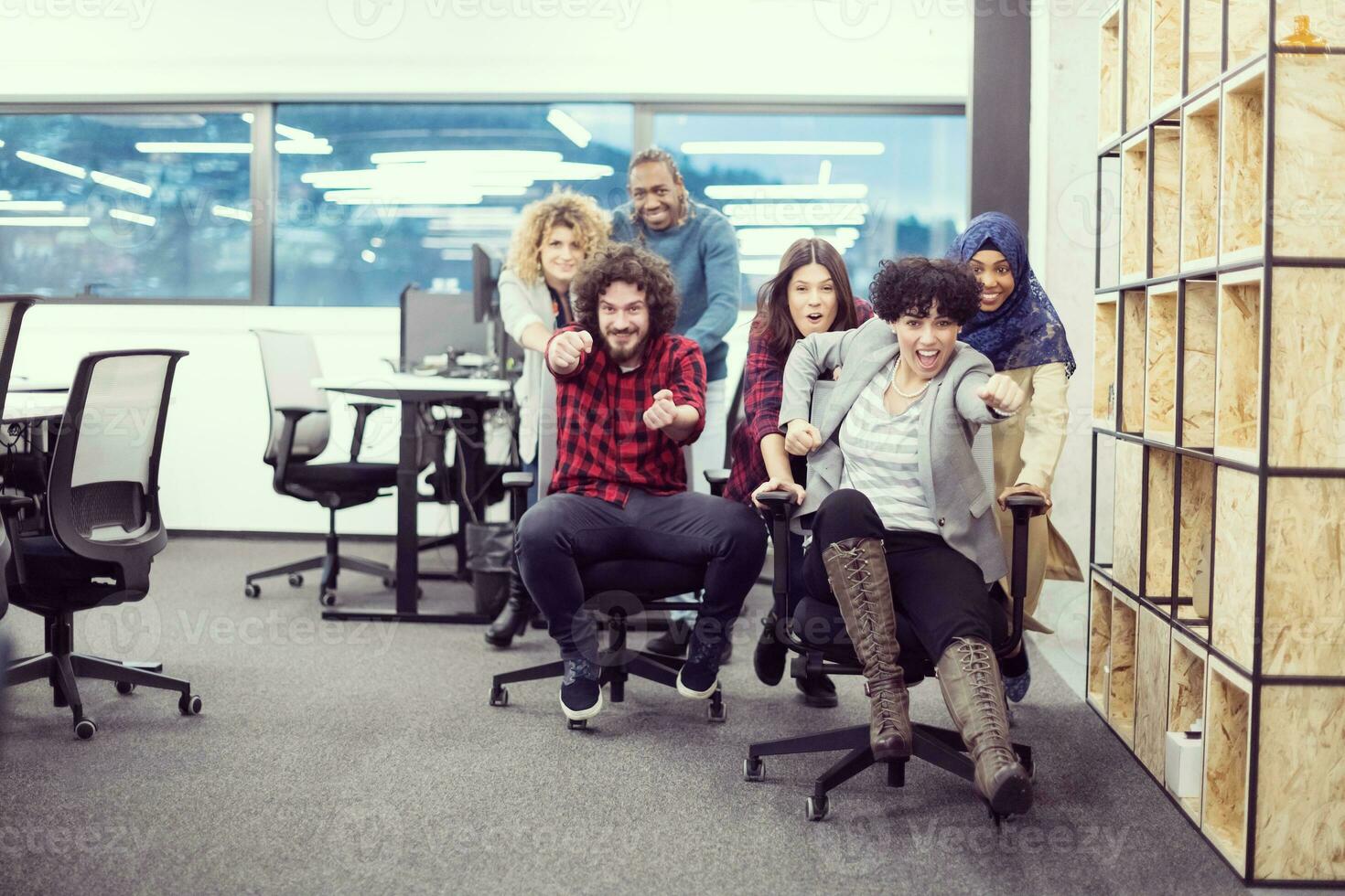 equipo de negocios multiétnico corriendo en sillas de oficina foto