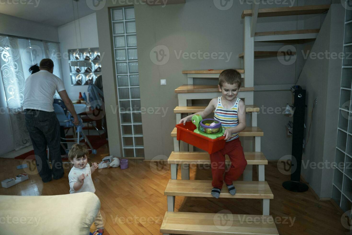 niño pequeño jugando y llevándole juguetes a su hermana foto