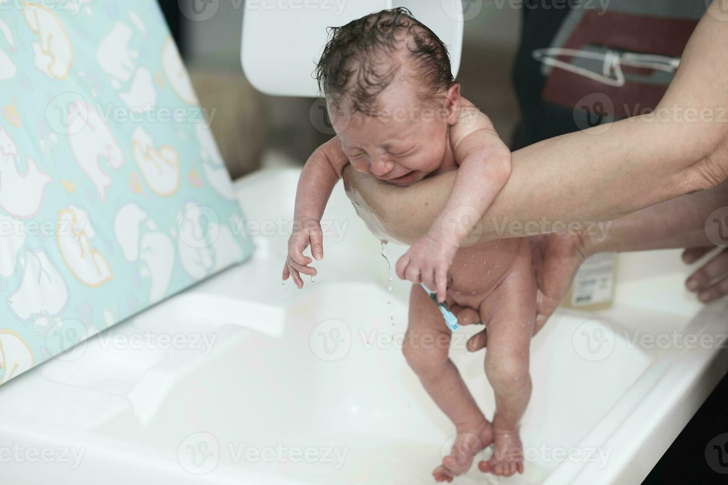 Newborn baby girl taking a first bath photo