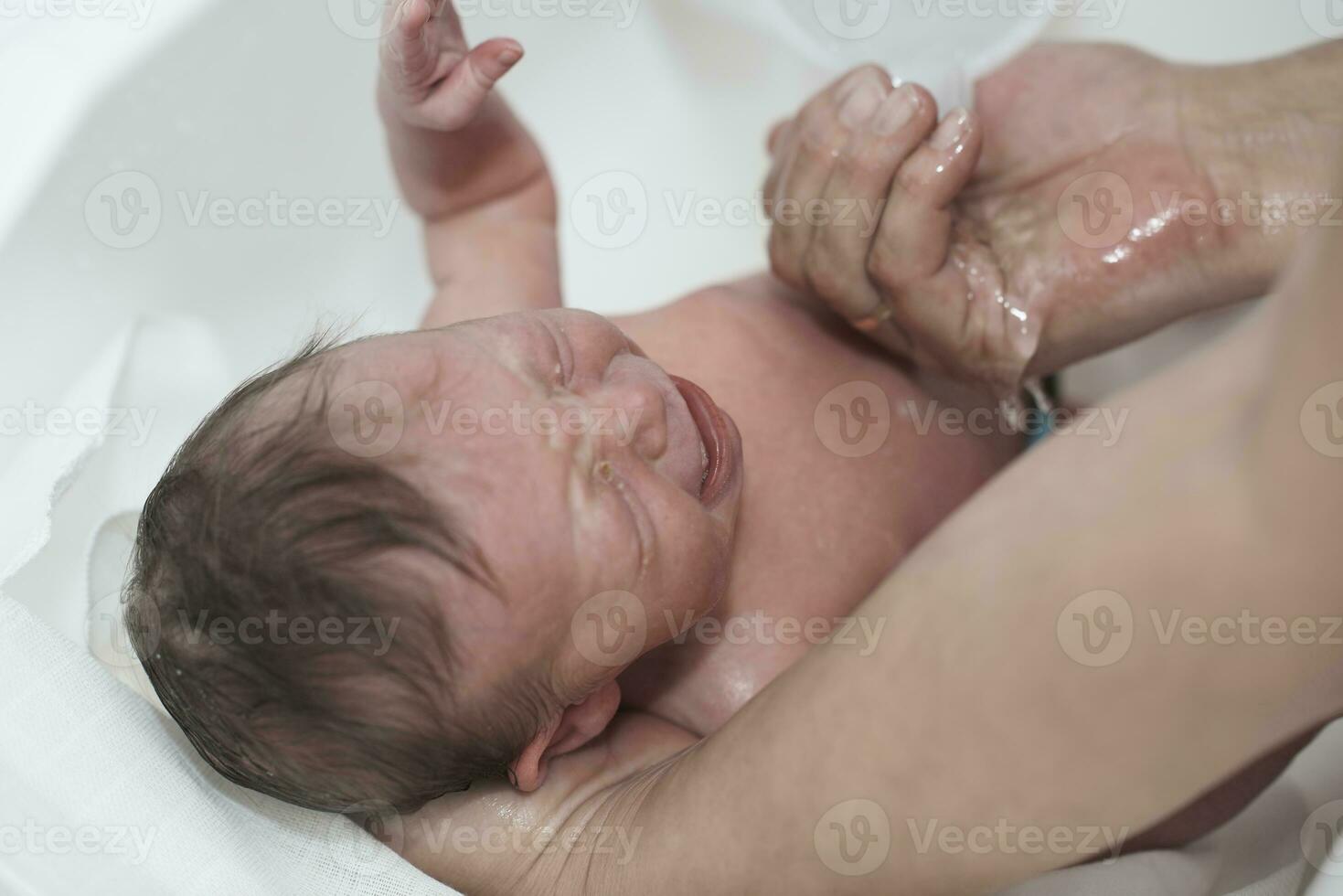 Newborn baby girl taking a first bath photo