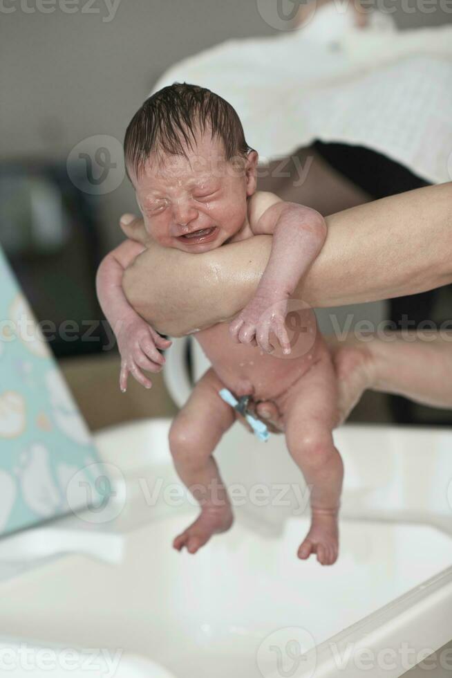 Newborn baby girl taking a first bath photo